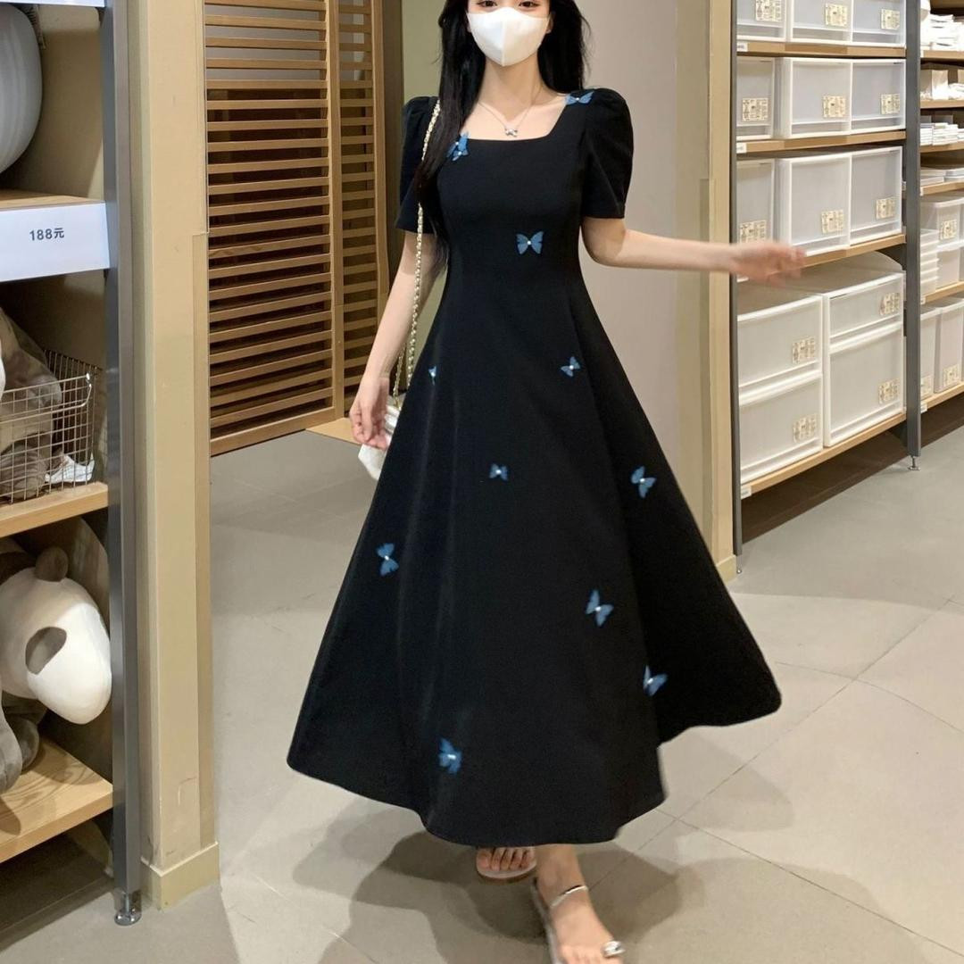 فستان أسود صيفي أنيق بتصميم فاخر مزين بفراشات ثلاثية الأبعاد، يمنح مظهرًا أنثويًا راقيًا ويبرز القوام بشكل أنحف