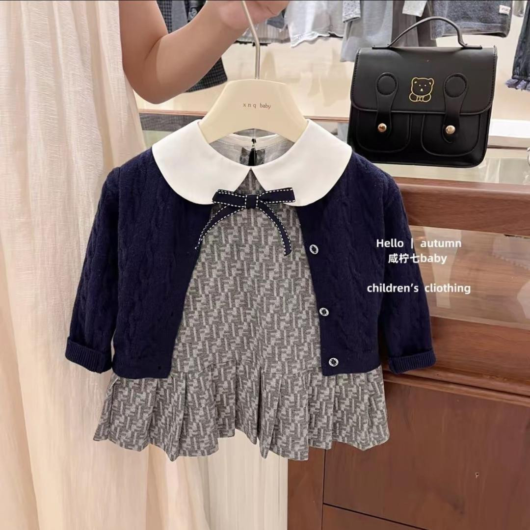 طقم بناتي كوري أنيق لموسم الخريف، يتكوّن من سترة تريكو باللون الكحلي مع فستان بحمالات مزين بفيونكة لطيفة، تصميم عصري وعملي يمنح طفلتك إطلالة دافئة