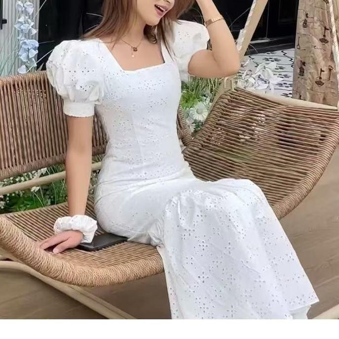 فستان أبيض بتصميم فاخر بتفاصيل مفرغة أنيقة، خامة خفيفة لصيف منعش، بطول تحت الركبة وقصة ذيل السمكة الضيقة لإطلالة أنثوية